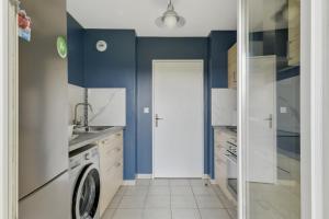 a kitchen with blue walls and a washing machine at Chic apartment with superb view of the eiffel tower in Saint-Denis