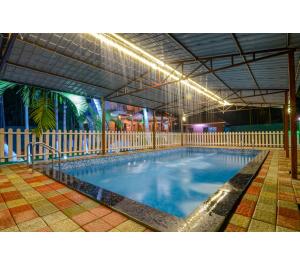 a large swimming pool with blue water in a building at Bhumi Cottage in Revadanda