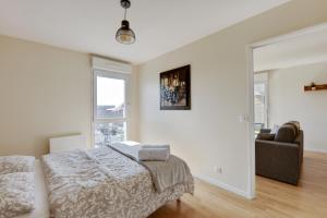 a white bedroom with a bed and a couch at Chic apartment with superb view of the eiffel tower in Saint-Denis