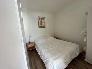 a small bedroom with a white bed and a table at PrésidentA8 in Le Touquet-Paris-Plage
