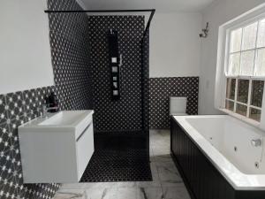 y baño en blanco y negro con bañera y lavamanos. en Berg River Living, en Velddrif