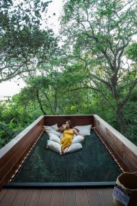 una mujer acostada sobre almohadas en una cama en una cubierta en Tierra Magnifica Boutique Hotel, en Nosara