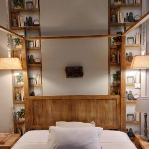 a bedroom with a wooden headboard and shelves with books at Au Bonheur d'Alphonse in Lusignan-Petit