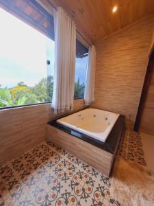 una vasca da bagno in una stanza con una grande finestra di Luar de Minas suites a Lavras Novas