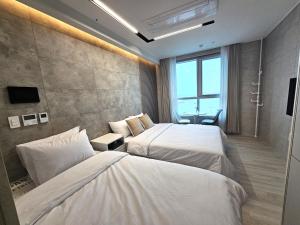 ein Hotelzimmer mit 2 Betten und einem Fenster in der Unterkunft Elliy's Room in Busan