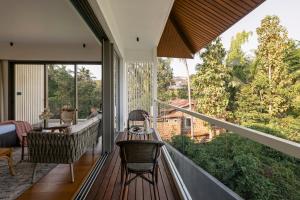 a balcony with a table and chairs and a view of trees at The Banyan Tree Villa B1 by Stay ALYF, Siolim in Siolim