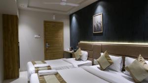 ムンバイにあるNew Amber Palace Hotelの黒い壁のホテルルームで、ベッド2台が備わります。