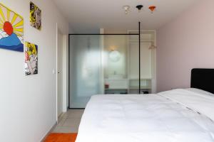 um quarto com uma cama branca e uma parede de vidro em ROOFTOP em Oostende
