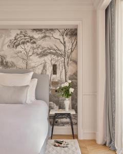 a bedroom with a painting of trees on the wall at Airelles Château de la Messardière in Saint-Tropez