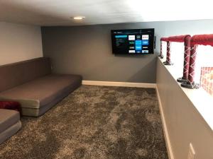 a living room with a couch and a flat screen tv at Hockey Themed Room with Wooded Trails in Benzonia