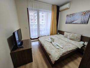 a bedroom with a bed with a dresser and a tv at Elegantz Apartments 2 in Varna City
