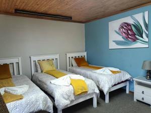 three beds in a room with blue walls at Chic Breeze in Bloemfontein