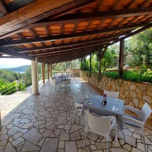 a patio with tables and chairs and a stone wall at Villa Šolta in Rogač