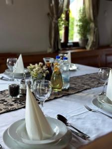 einen Tisch mit weißen Tellern und Gläsern auf einem weißen Tischtuch in der Unterkunft Gyarmati Panzió & Étterem in Veszprém