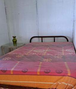 een bed met een roze en oranje deken erop bij El rincón de blanquita in Cali