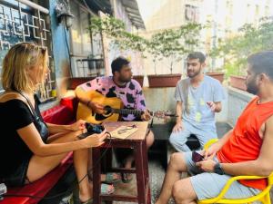 a group of people sitting around a table playing guitar at Stayvilla Hostel in Mumbai