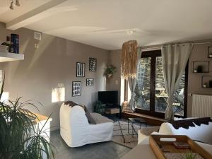 a living room with a white couch and a tv at Le Rêve in La-Roche-en-Ardenne