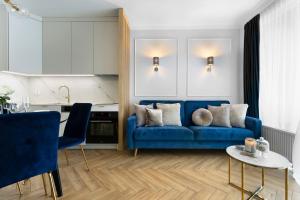 Elite Apartments Chlebova Premium في غدانسك: غرفة معيشة مع أريكة زرقاء ومطبخ