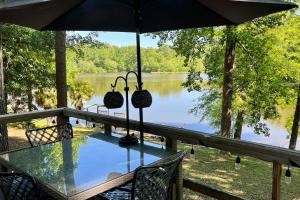 - une table avec des chaises et un parasol en face d'un lac dans l'établissement Romantic Lakefront Cottage with Boat Dock on Quiet Cove, à Anderson