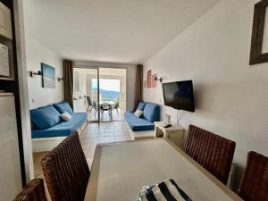 ein Wohnzimmer mit einem blauen Sofa und einem Tisch in der Unterkunft Les Restanques 4027 vue mer grande terrasse in Grimaud