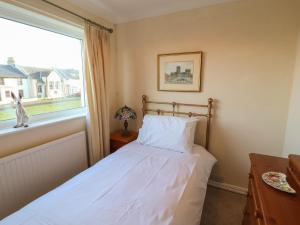 een slaapkamer met een bed en een raam bij Woodbine Cottage in Maryport