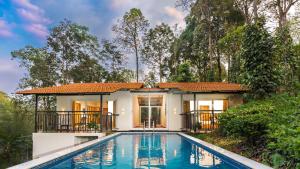 a villa with a swimming pool in front of a house at Tealawn Pool Villa, Munnar in Munnar