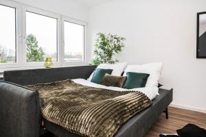 een bed in een kamer met een bank en ramen bij Artful Stay for 4 in Krefeld