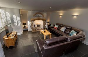 a living room with a leather couch and a fireplace at Revelstoke Park House in Noss Mayo