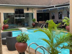 a swimming pool with chairs and plants in front of a house at Palazzo Dumont Hotel in Ikota