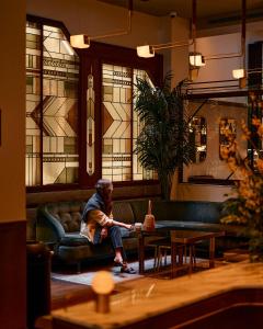 a man sitting on a couch in a room with stained glass at The Evelyn NoMad in New York