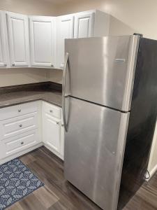 a stainless steel refrigerator in a kitchen with white cabinets at Brand new en-suite private bath next Camden yard , convention center in Baltimore