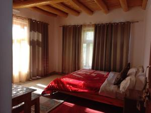 zoz Aryan Valley في Dah: غرفة نوم بها سرير مع أغطية ونوافذ حمراء