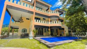 an exterior view of a large house with a swimming pool at Homestay Seri Pangkor in Pangkor
