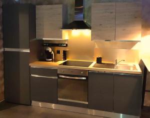 a stainless steel kitchen with a sink and a stove at La Secrète in Barlin