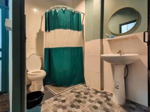a bathroom with a green shower curtain and a toilet at Sangthong Heritage hotel โรงแรมแสงทองเฮอริเทจ in That Phanom