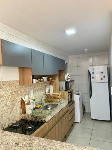 La cuisine est équipée d'un réfrigérateur blanc et d'un évier. dans l'établissement Apartamento 02 quartos para o Carnaval - Olinda, à Olinda