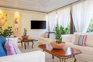 a living room with white furniture and a tv at Le Relais La Borie in Búzios