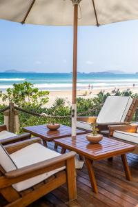 um pátio com mesas e cadeiras e a praia em Le Relais La Borie em Búzios