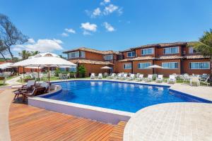 a pool with chairs and umbrellas in front of a hotel at Le Relais La Borie in Búzios