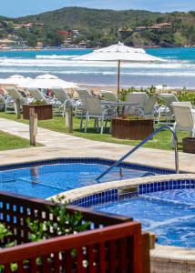a swimming pool with chairs and a beach at Le Relais La Borie in Búzios