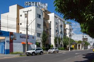 two cars parked on a street in front of a building at Hotel Apollo in Uberlândia