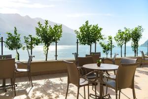 a patio with tables and chairs and a view of the ocean at Hotel Villa Dirce in Limone sul Garda