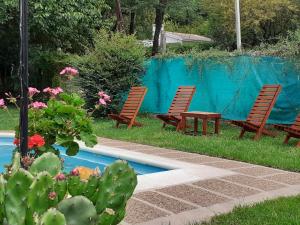 3 Stühle und ein Tisch neben einem Pool in der Unterkunft CASONA DELVUELO in Unquillo