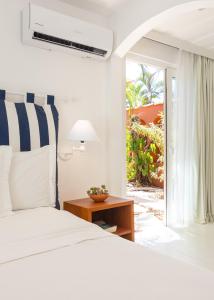 a white bedroom with a bed and a window at Le Relais La Borie in Búzios