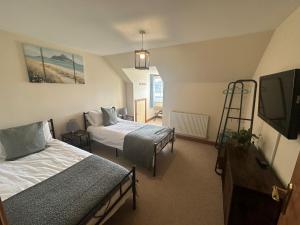 a room with two beds and a flat screen tv at Riverside in Brecon
