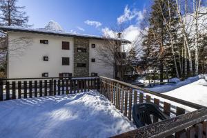 ein Haus mit einem schneebedeckten Zaun in der Unterkunft Appartamento Anne in Entrèves