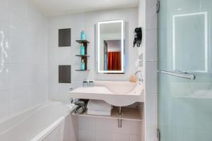 Un baño con lavabo, bañera y espejo. en Novotel Paris Centre Bercy, en París
