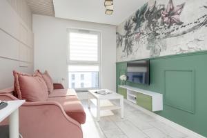 a living room with a pink couch and a tv at Motława River Old City Gdańsk Apartment by Renters in Gdańsk