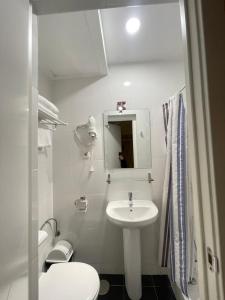 Baño blanco con lavabo y aseo en Hostal Oliver, en Madrid