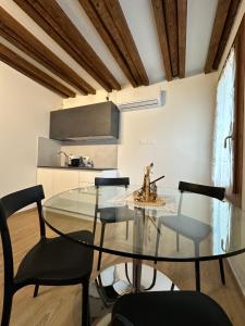 uma sala de jantar com uma mesa de vidro e cadeiras em Sora al Ponte em Chioggia